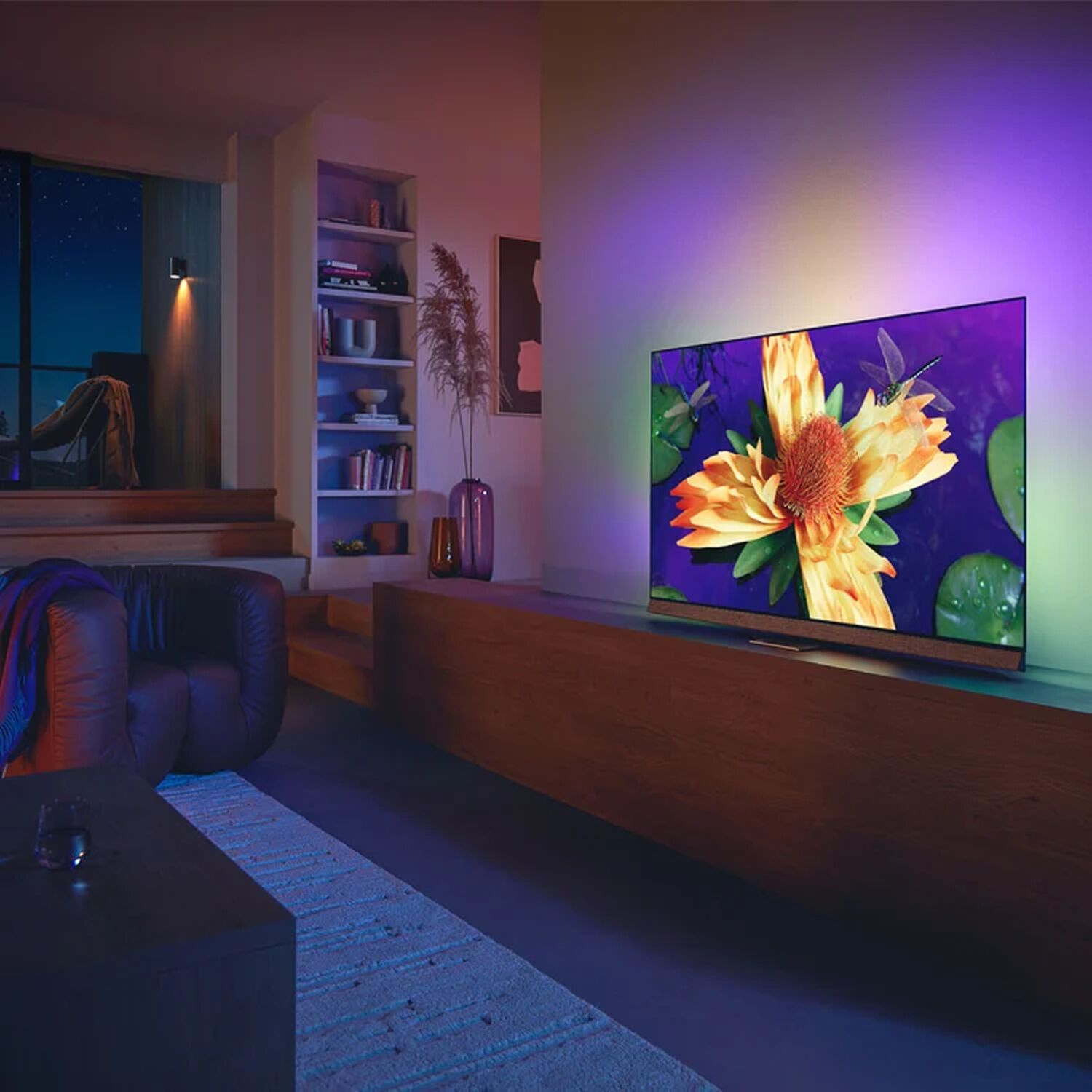 Philips OLED+907 in living room with purple, yellow and green lights behind TV