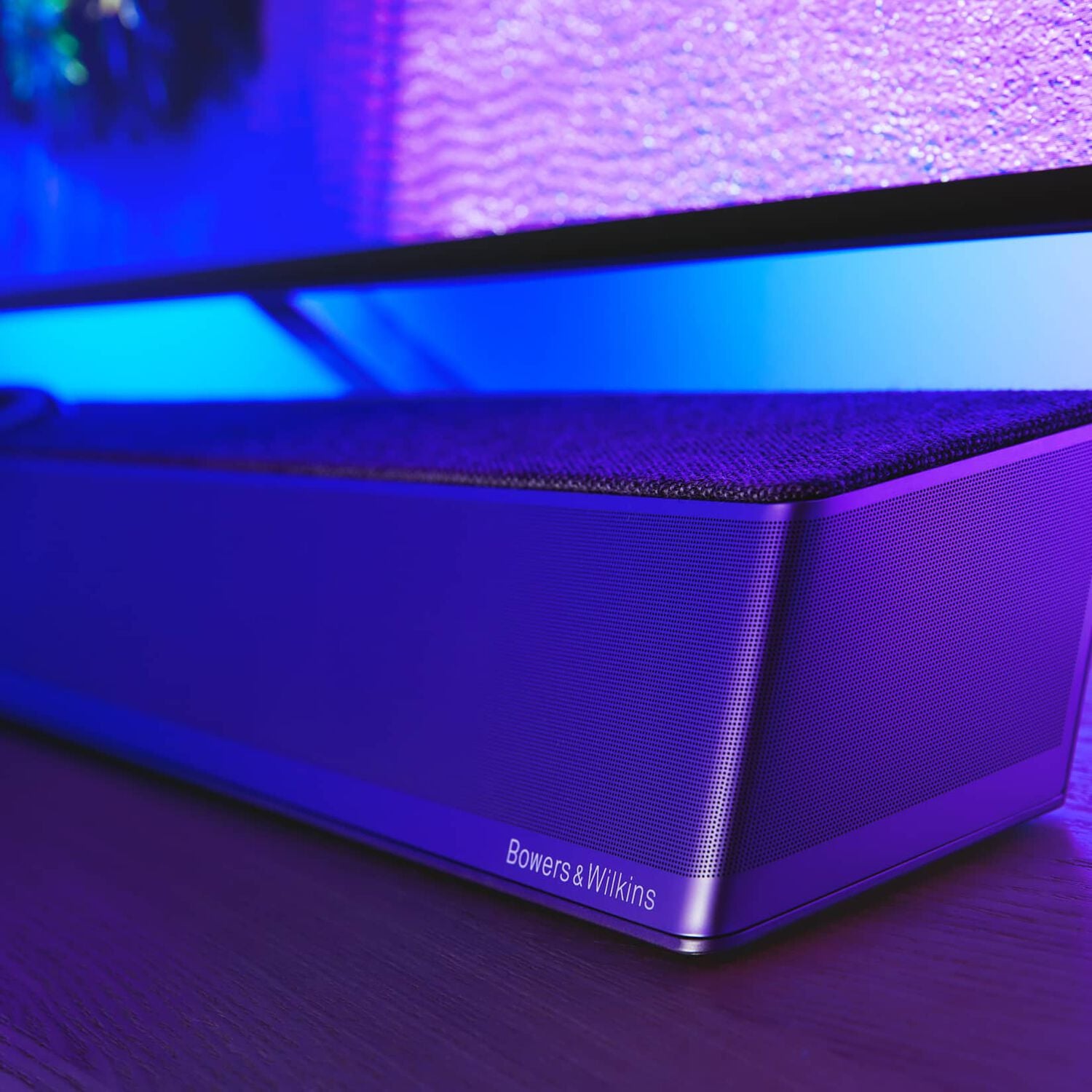 Silver Bowers & Wilkins soundbar below TV with blue illumination behind