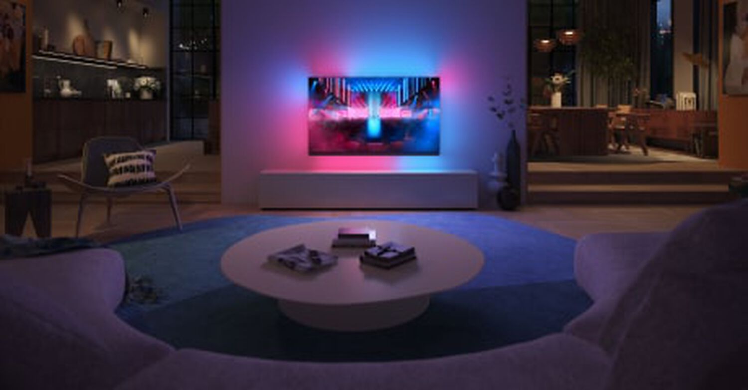 Philips OLED+909 wall mounted in living room with pink and blue lights behind TV