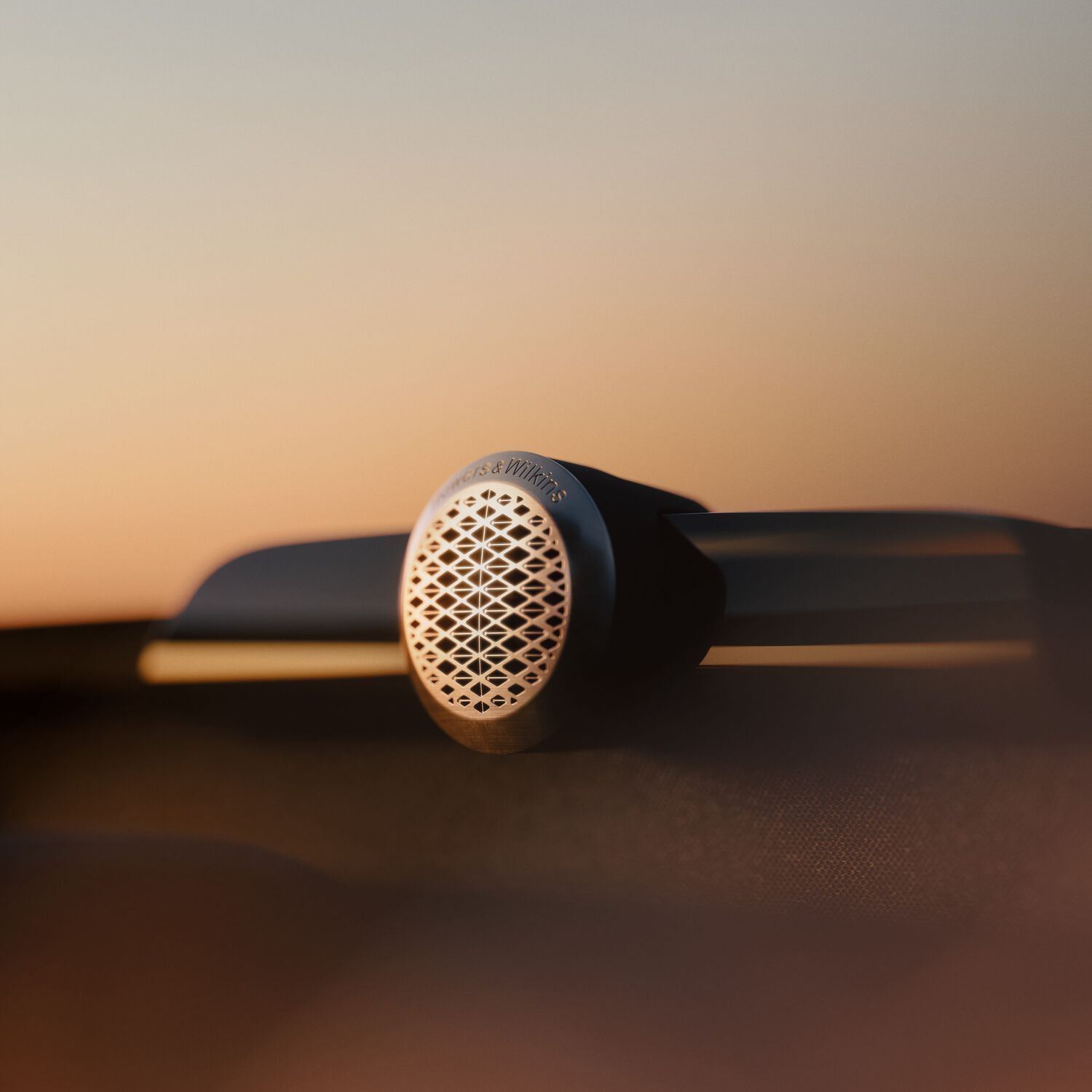 Small silver circular Bowers & Wilkins speaker with orange gradient background