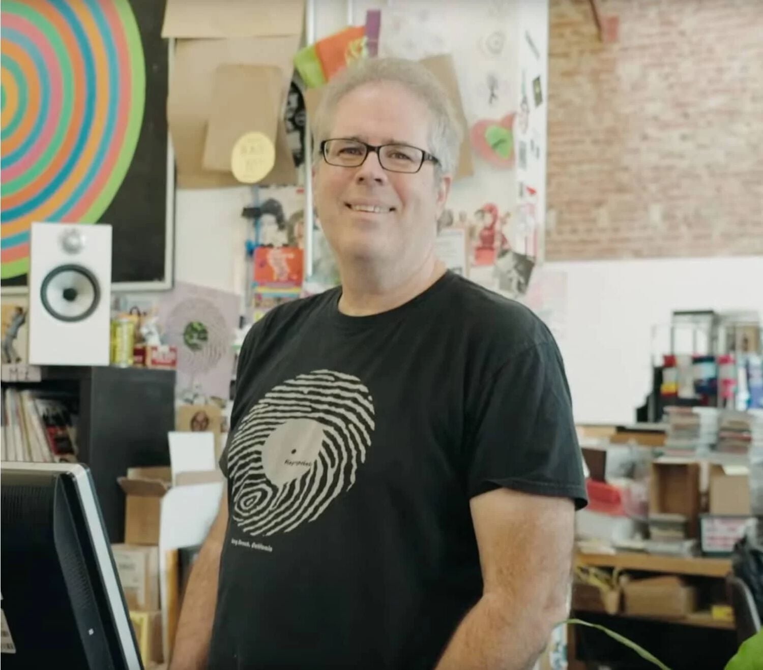 Man wearing graphic tee smiling in record store