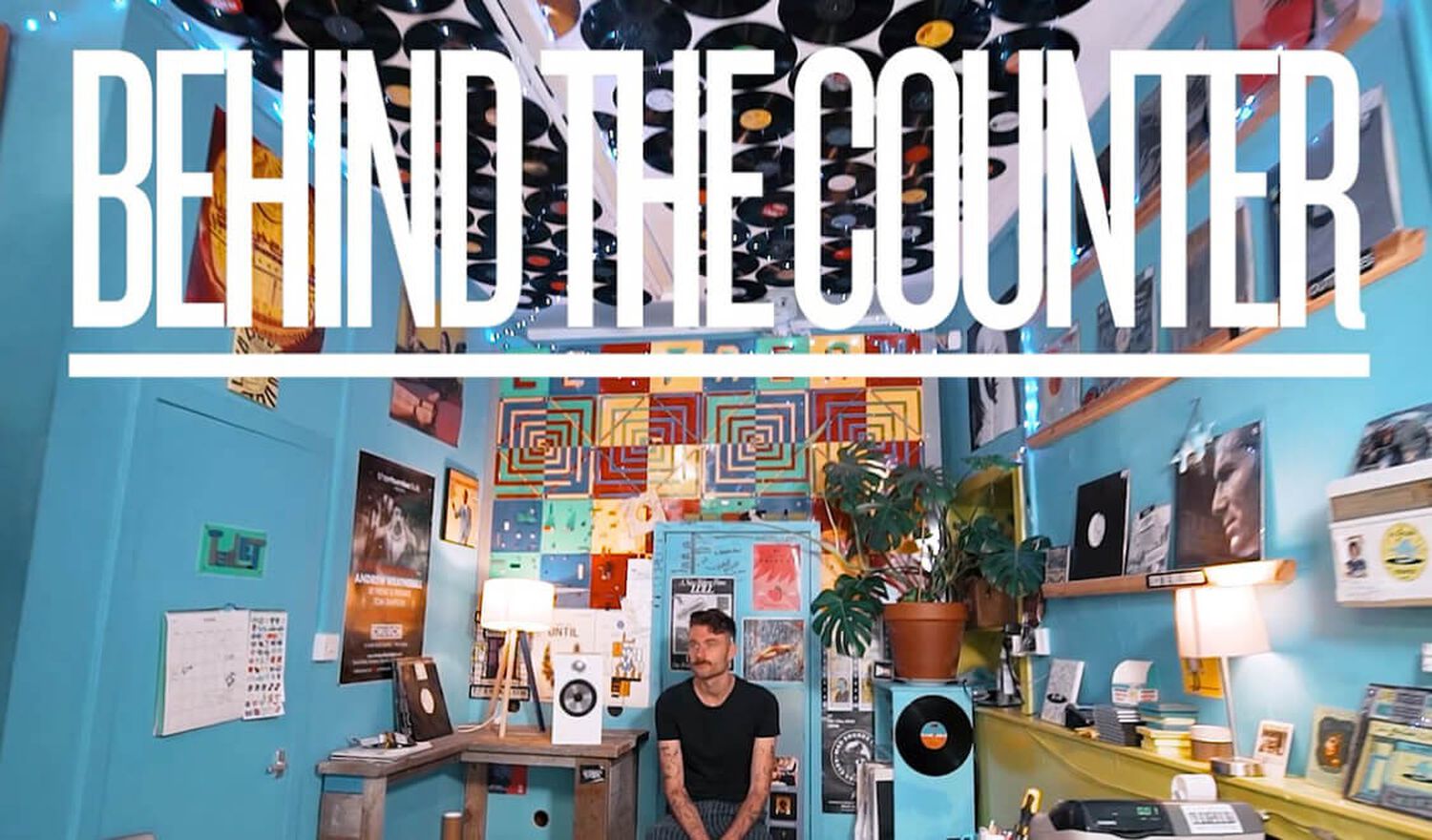 Man sitting in blue room with vinyl records on wall