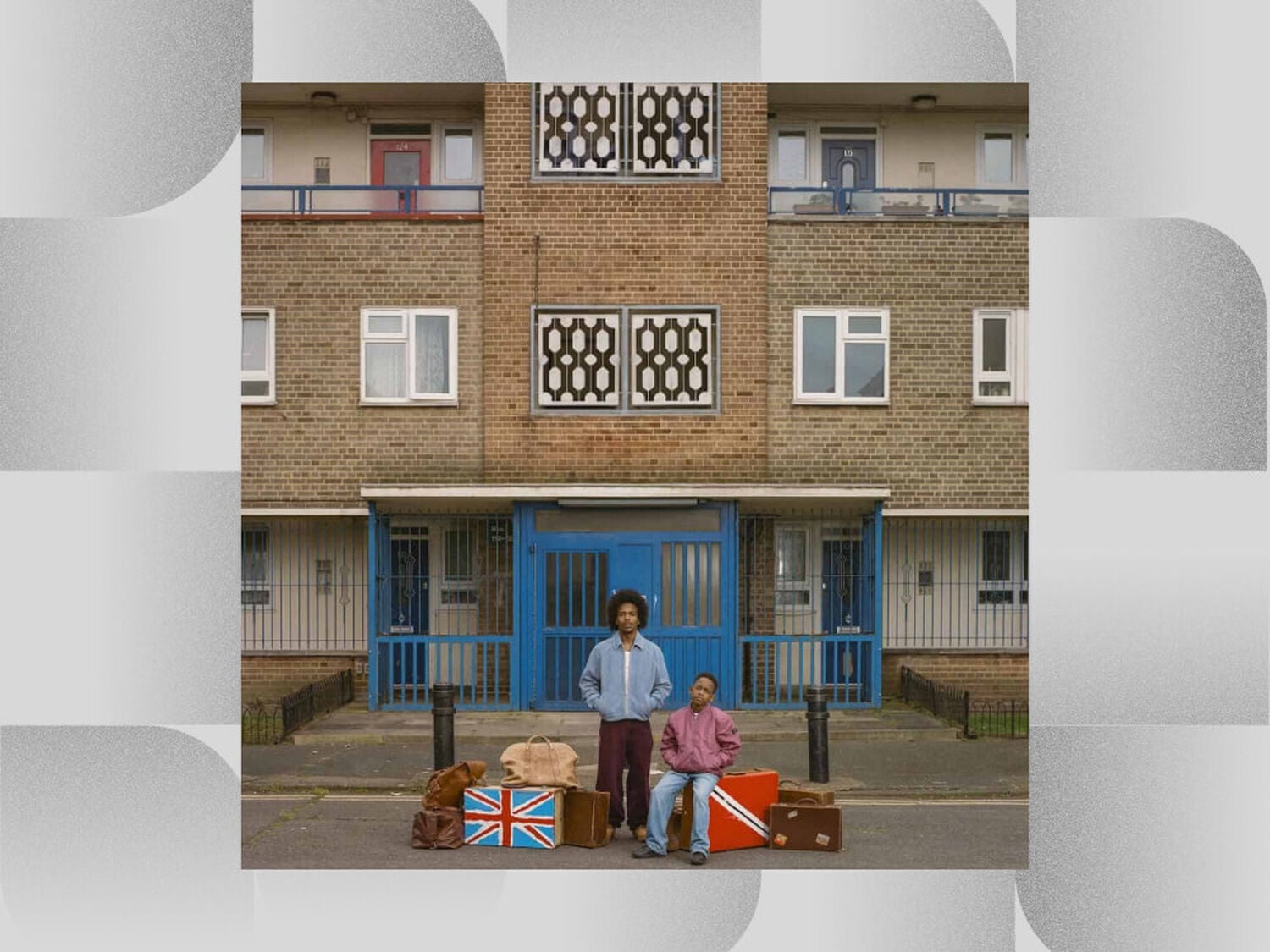Man and boy in front of beige brick building with luggage