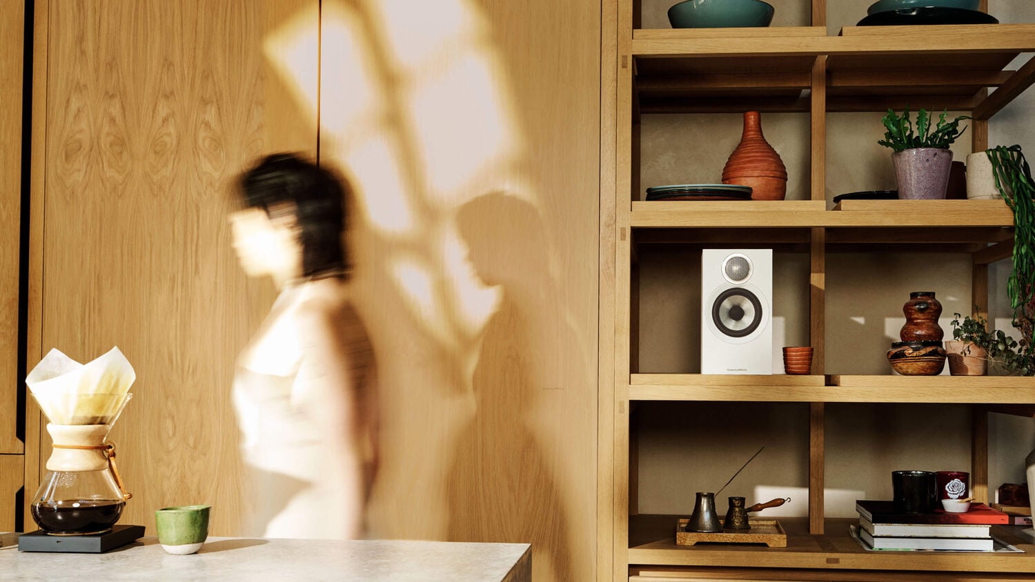 Someone walking by one white 606 S3 loudspeaker on a shelf