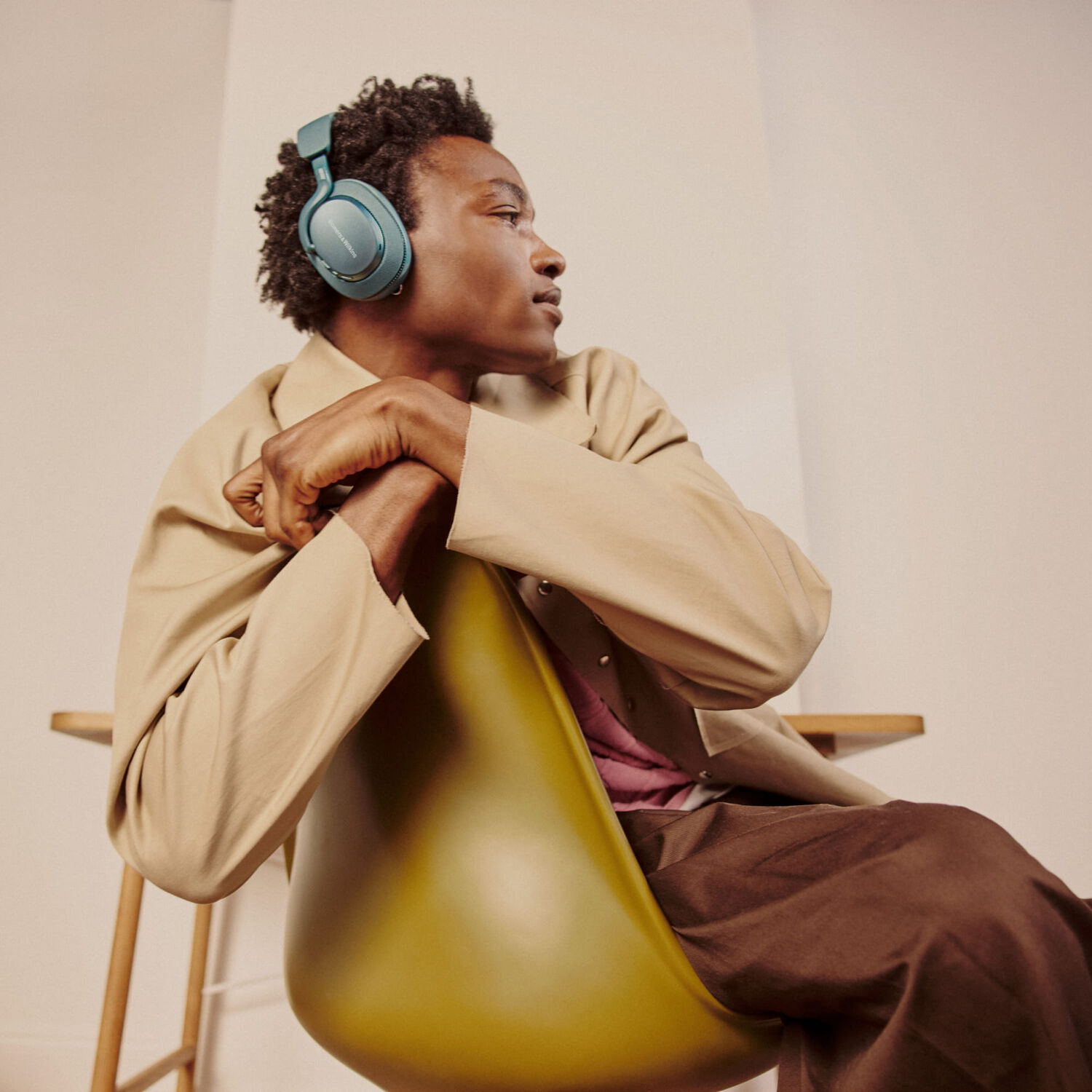 Man wearing blue over-ear headphones sitting in a chair facing right