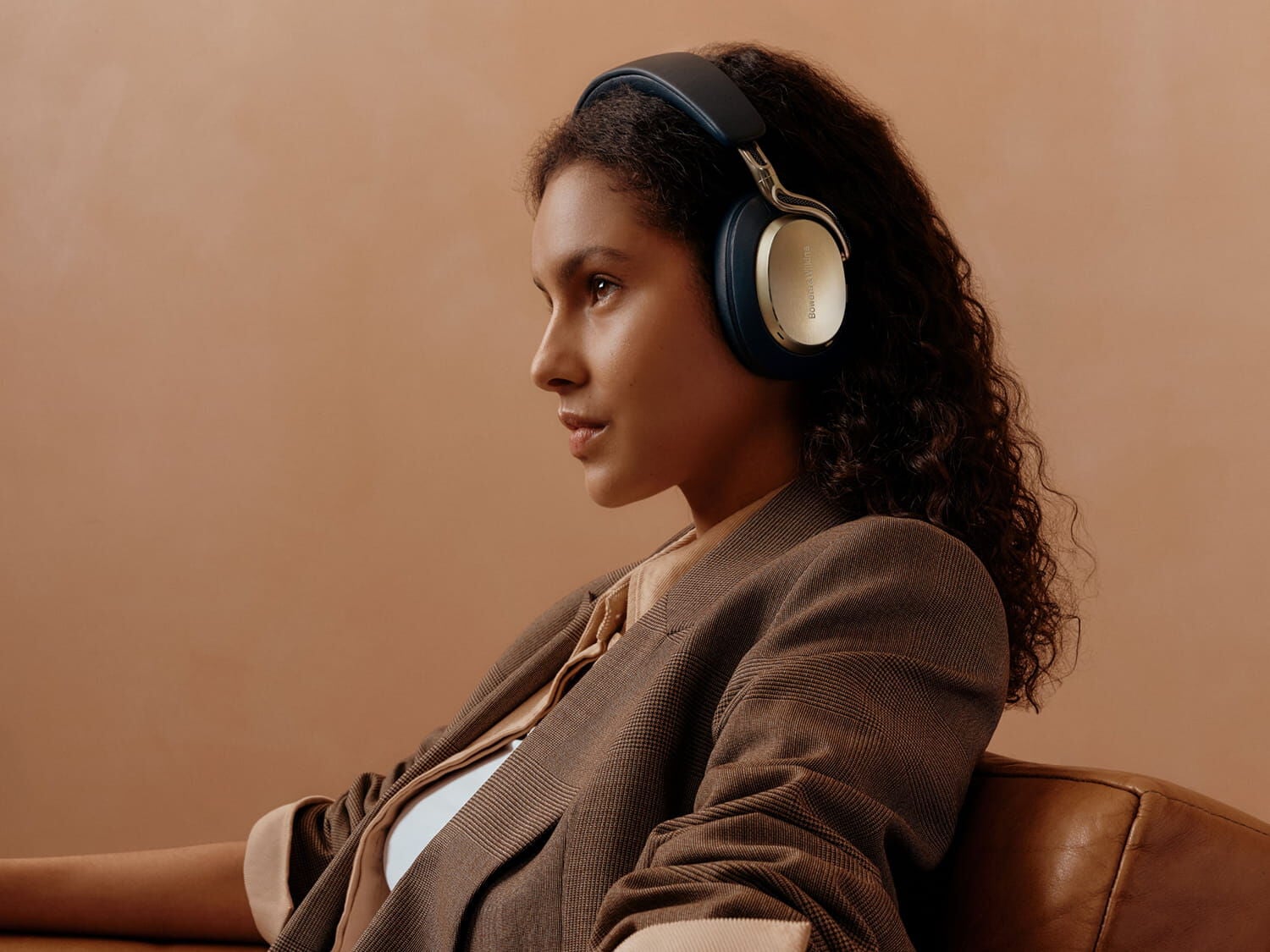 Woman wearing gold Px8 S2 facing left with beige background
