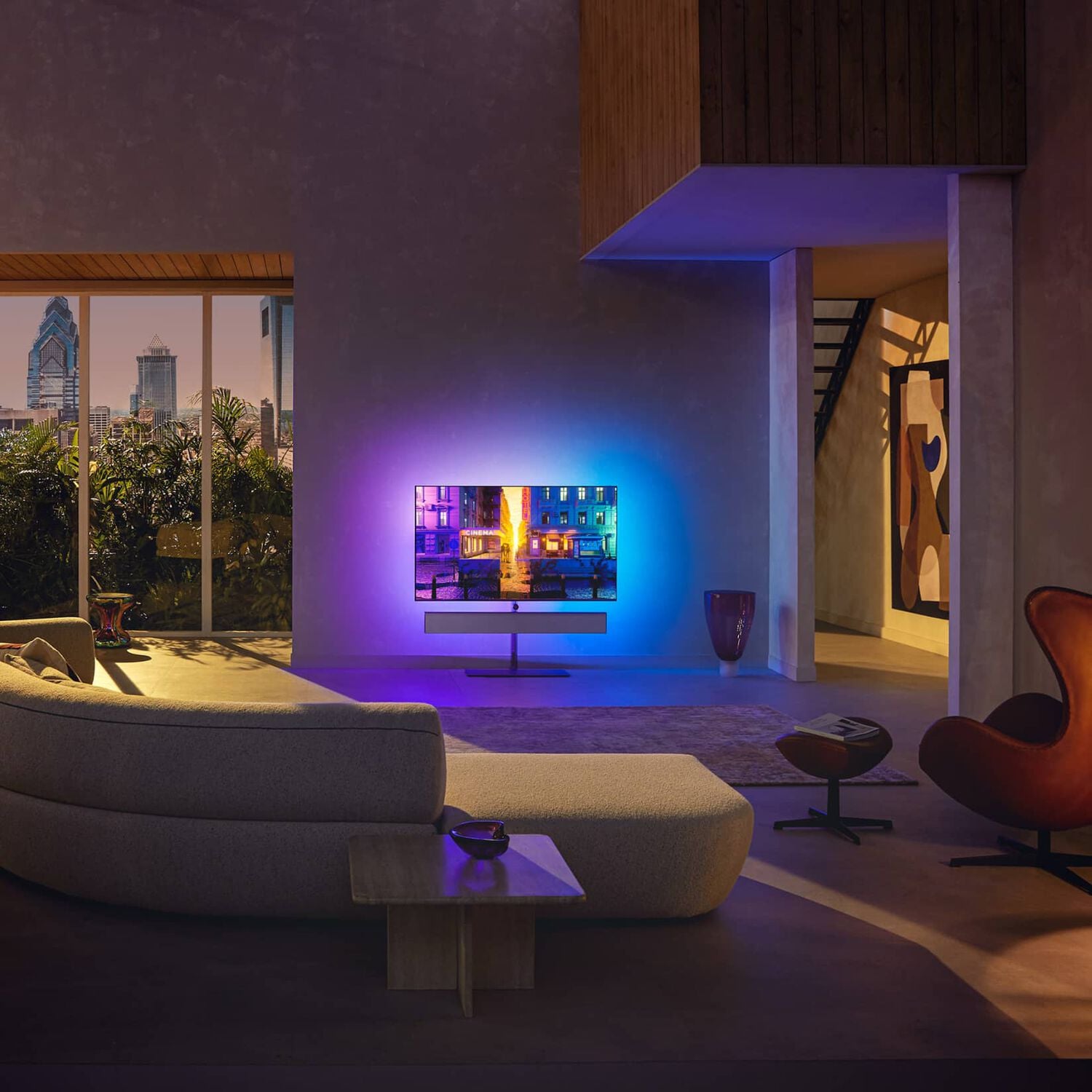 Living room with curved white sofa and TV with blue and purple lights with silver soundbar