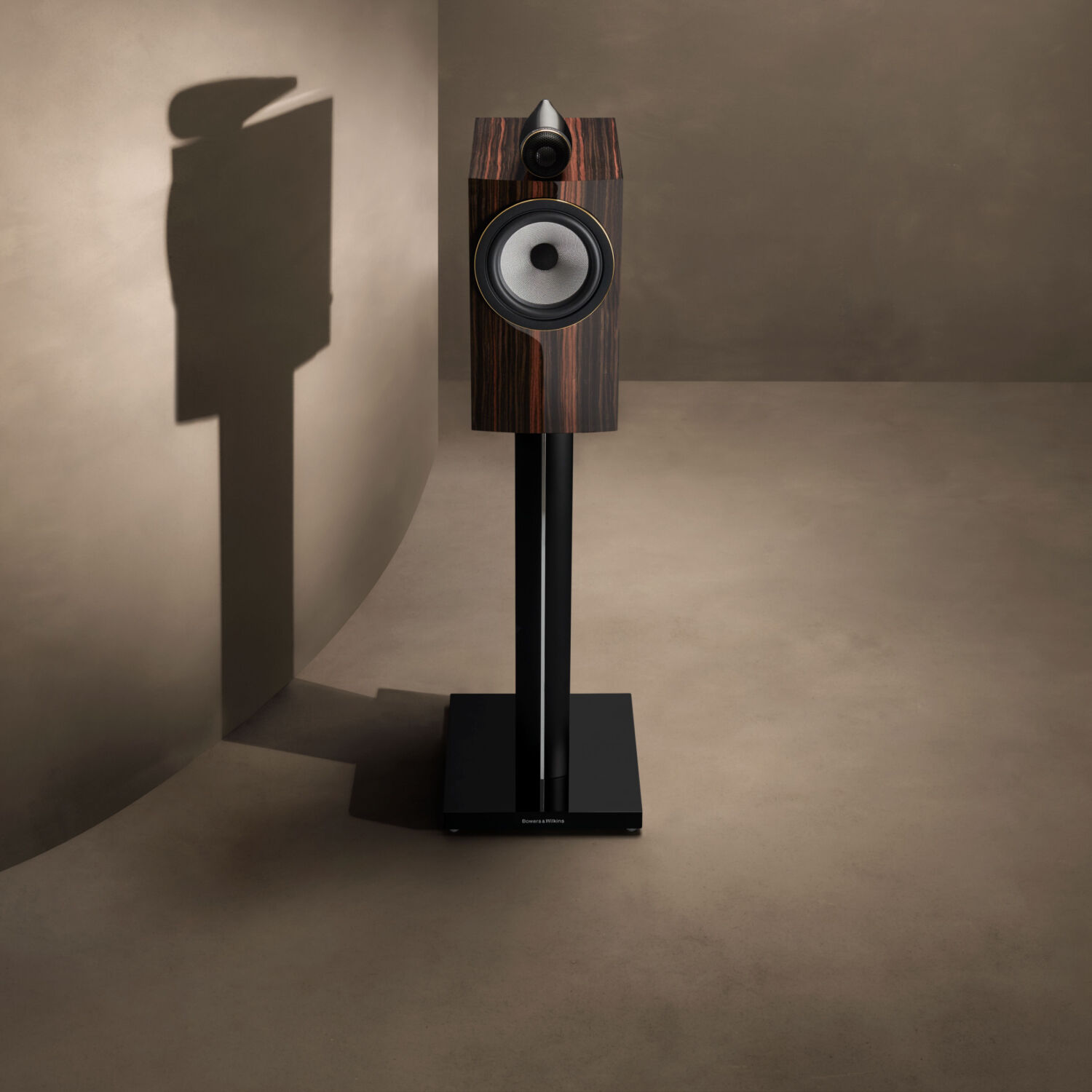 One brown loudspeaker in an empty room with light brown walls
