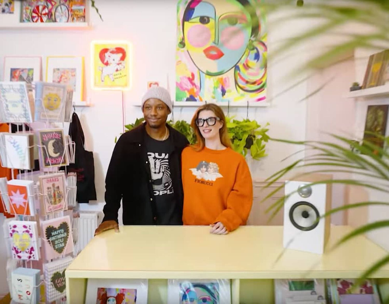 Man and woman standing behind counter in store with silver speaker