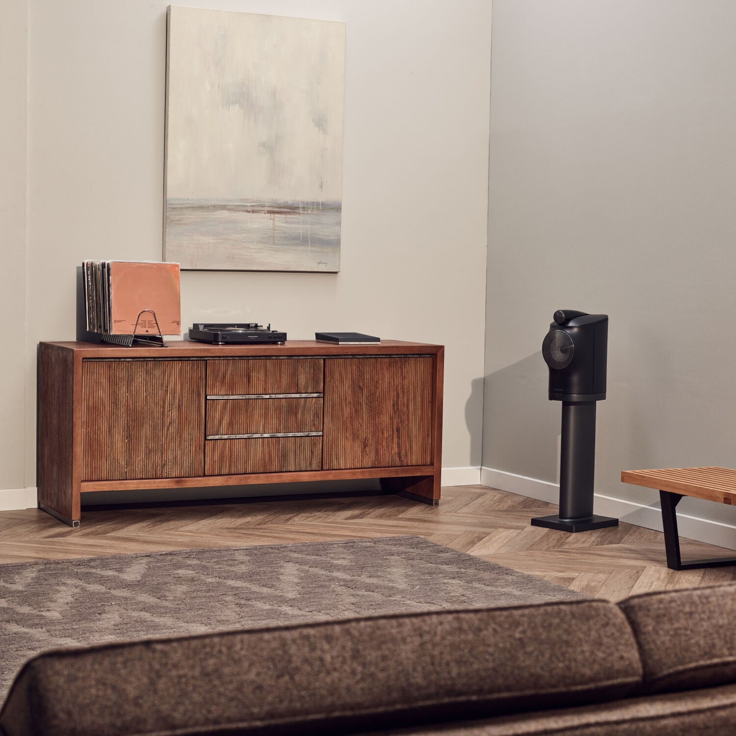 Black turntable on media console with vinyl records with black standing speaker to the right