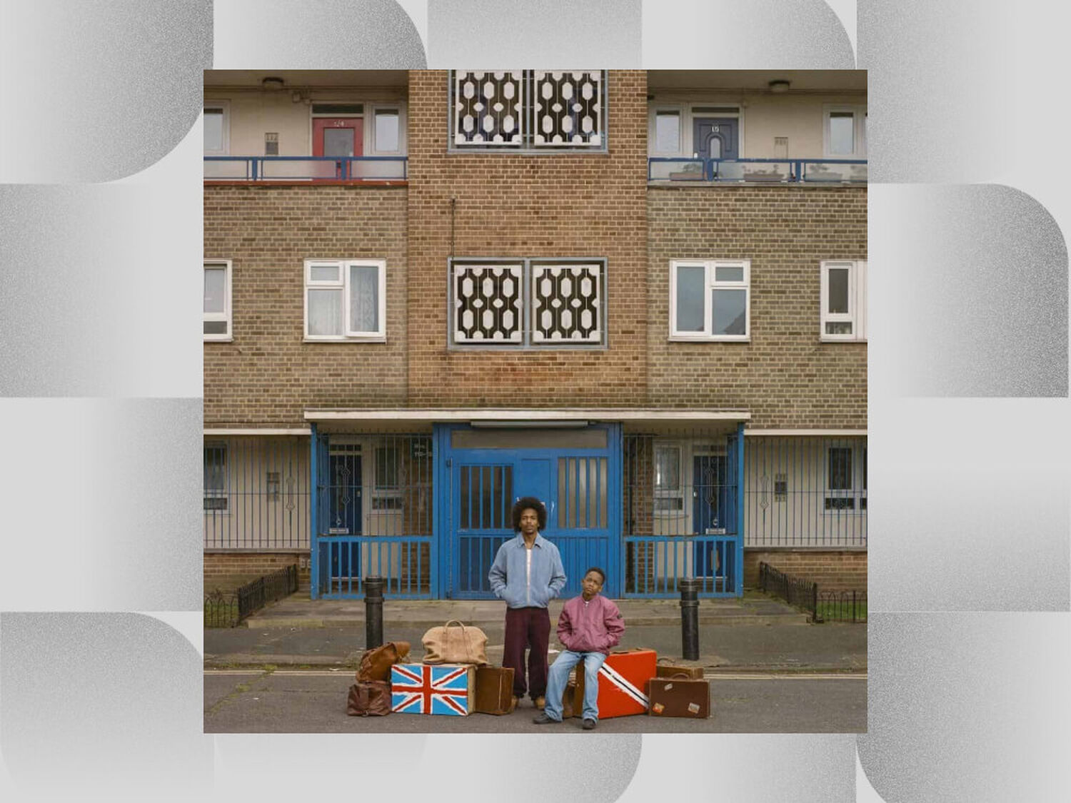 Man and boy in front of beige brick building with luggage