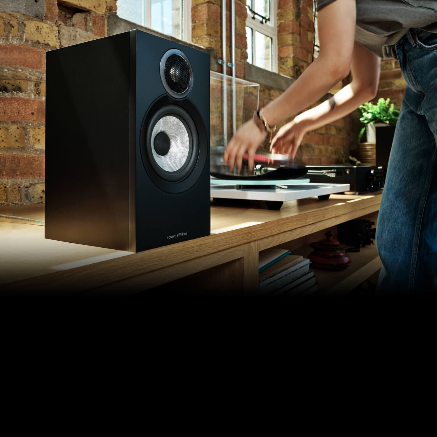Woman placing a vinyl record next to a speaker