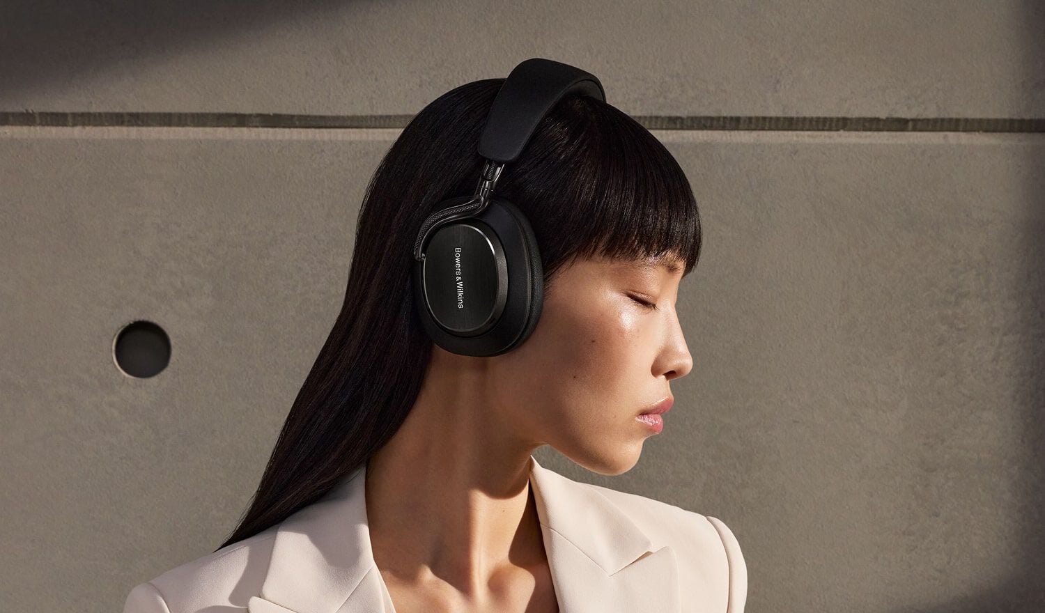 Woman wearing over-ear headphones facing right