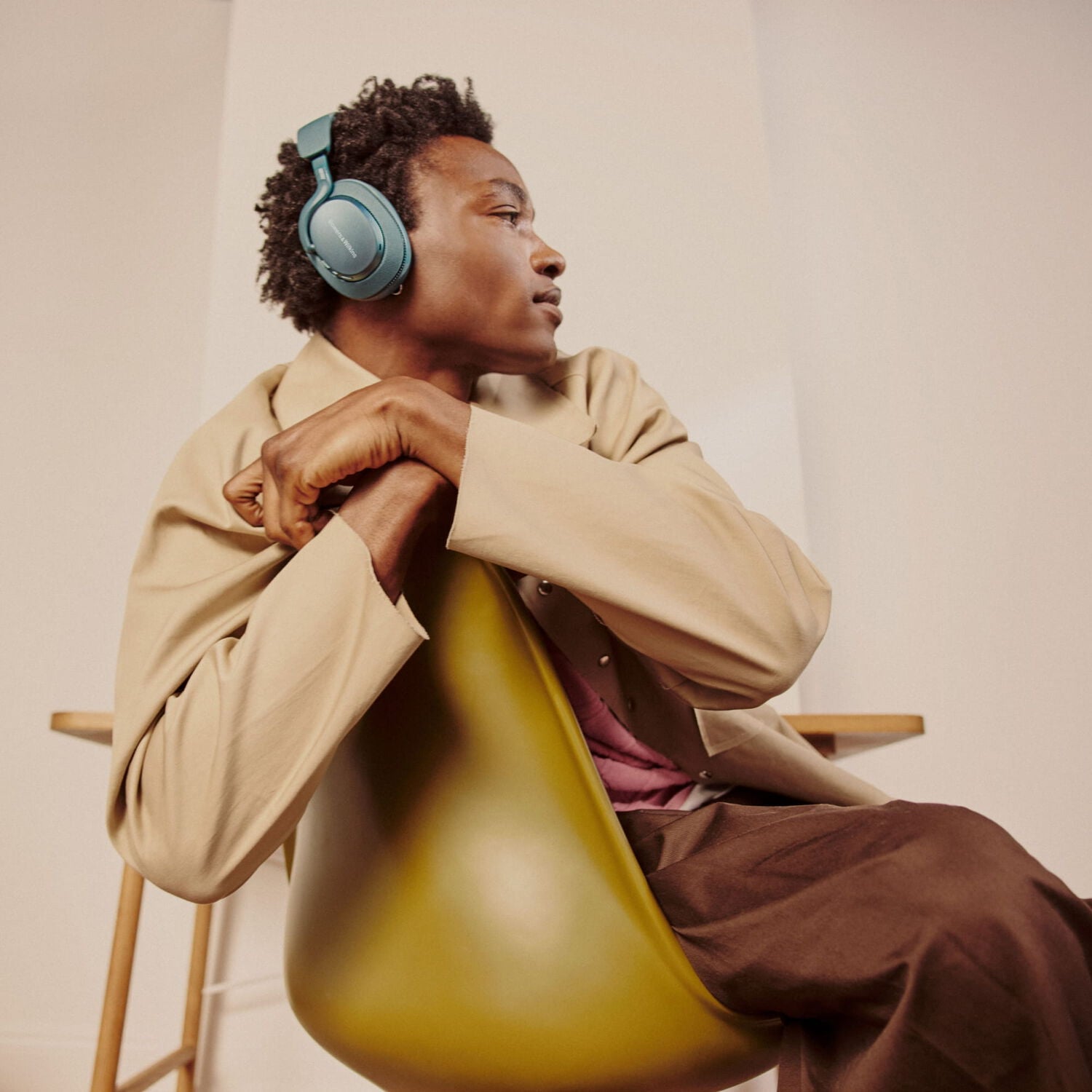 Man wearing blue over-ear headphones sitting in a chair facing right