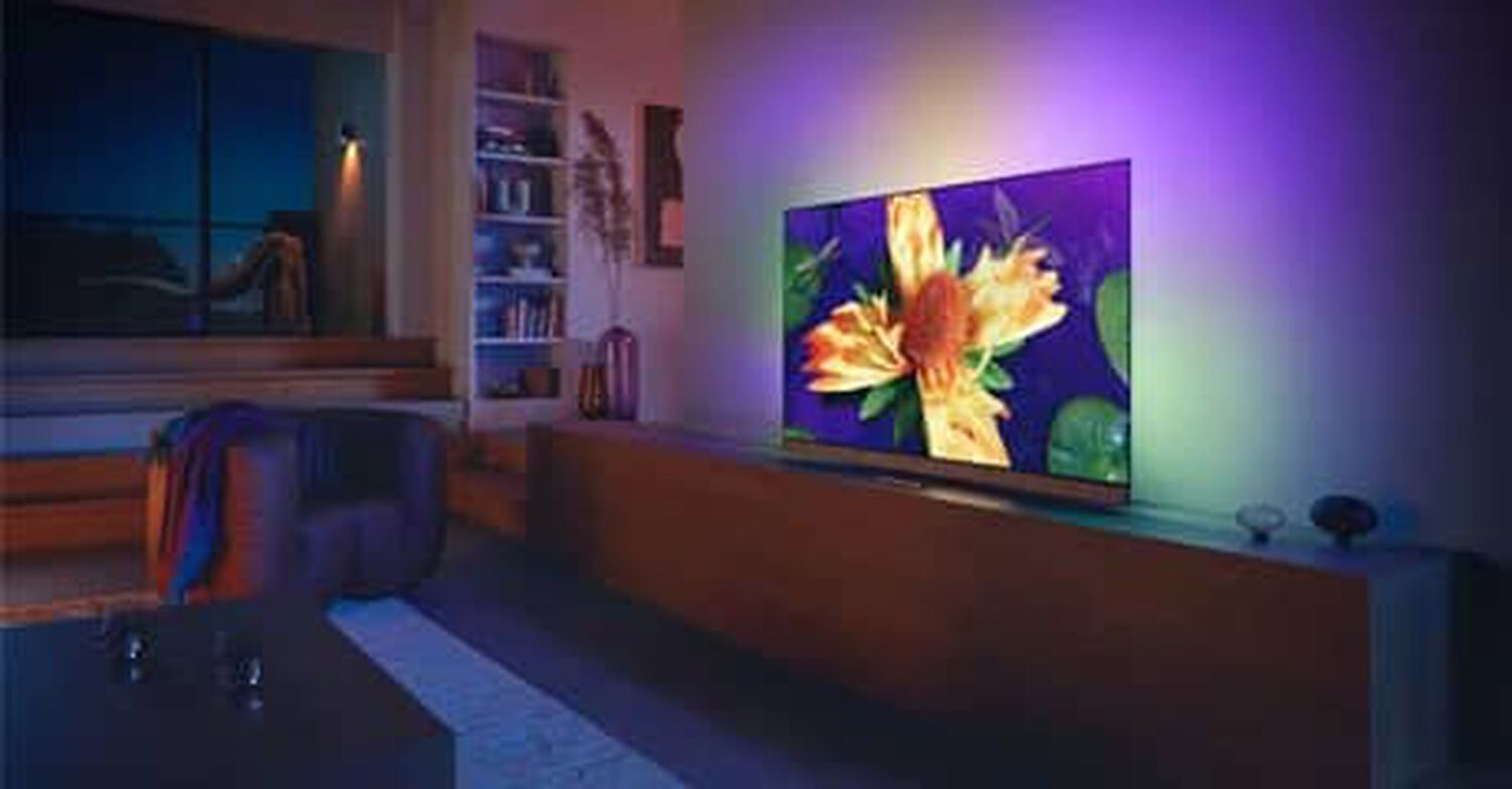 Philips OLED+907 in living room with purple, yellow and green lights behind TV