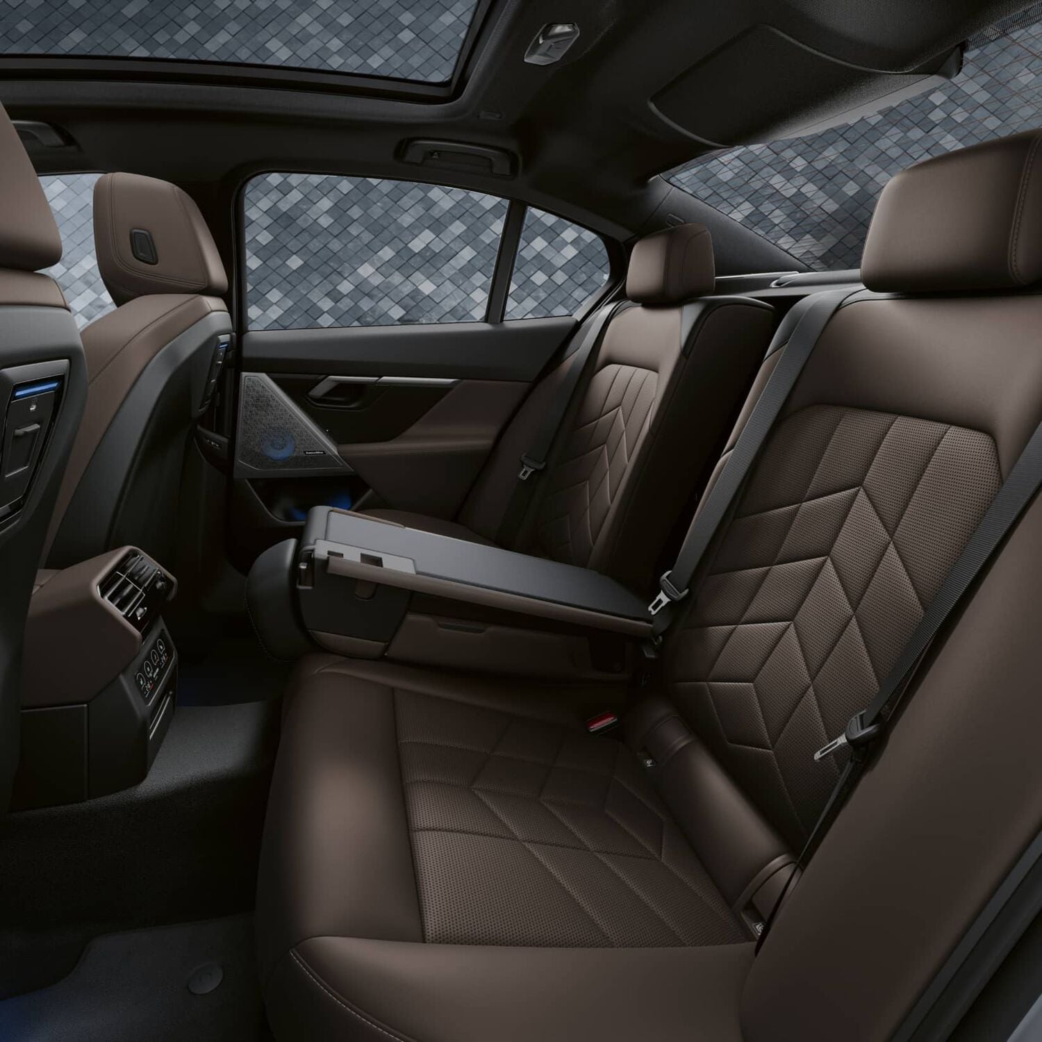 Back seat of car with brown leather interior with blue Bower & Wilkins car speakers