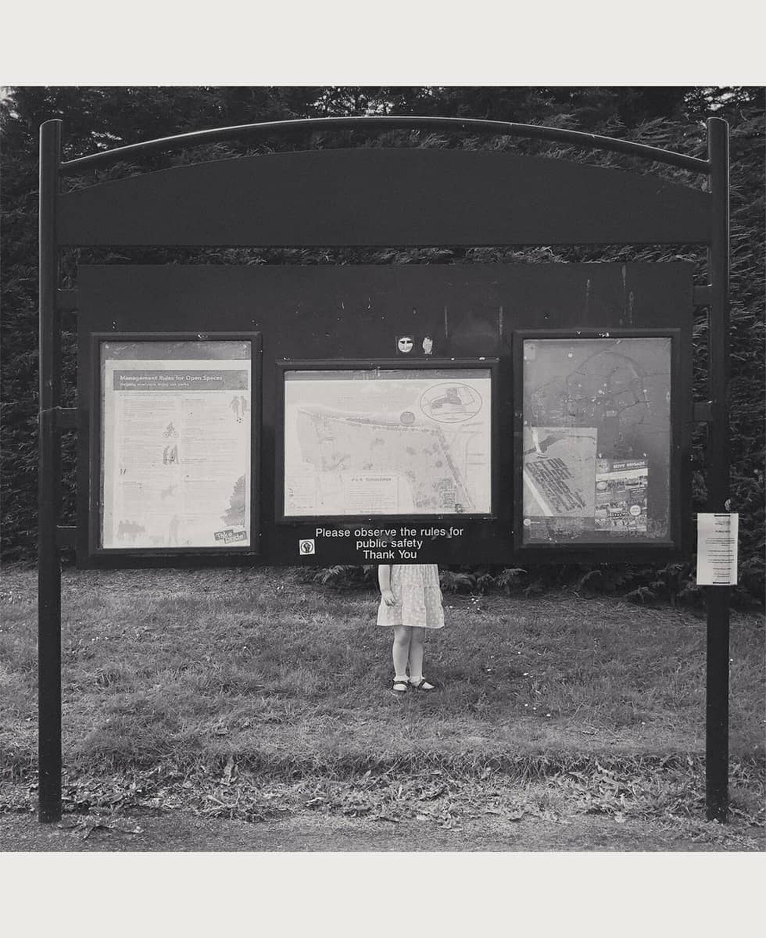 Child standing behind hiking trail map 
