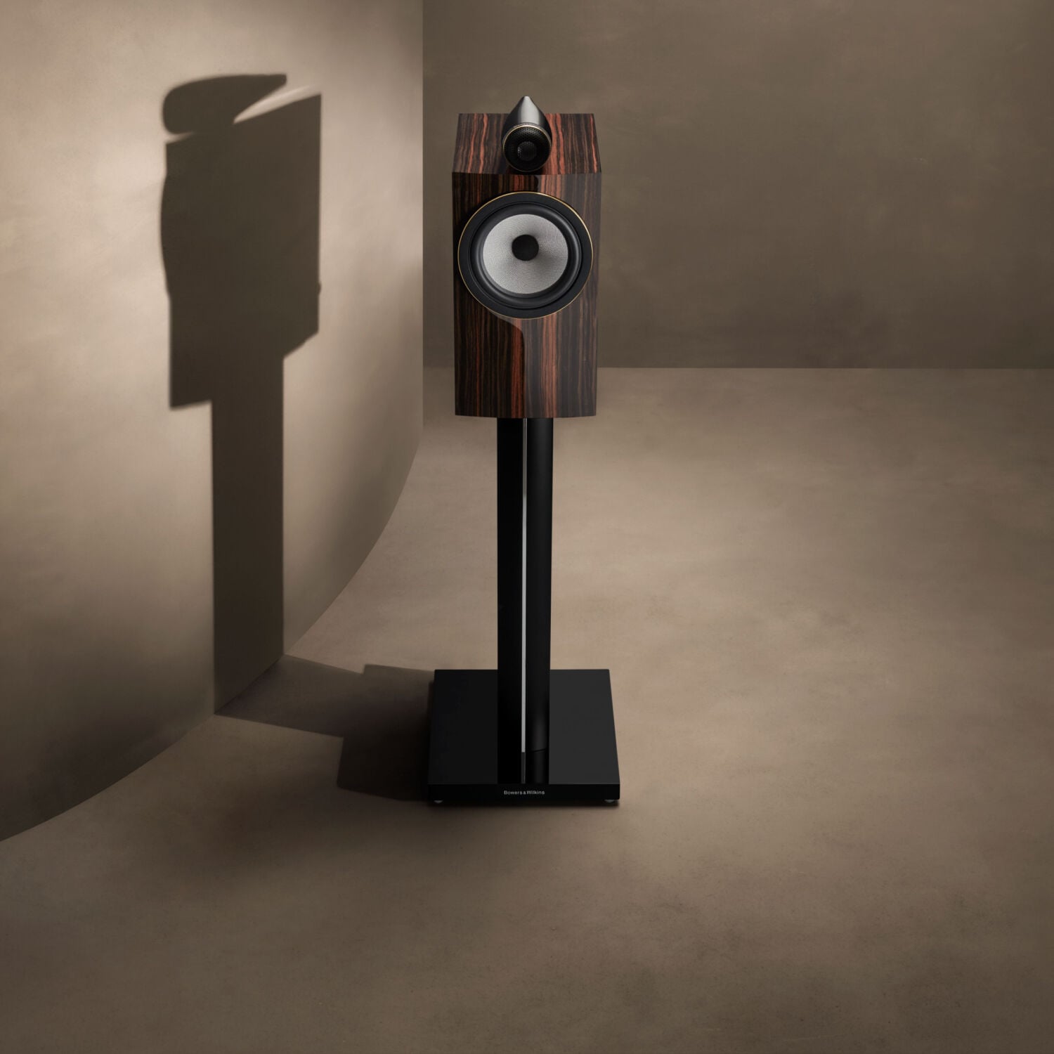 One brown loudspeaker in an empty room with light brown walls