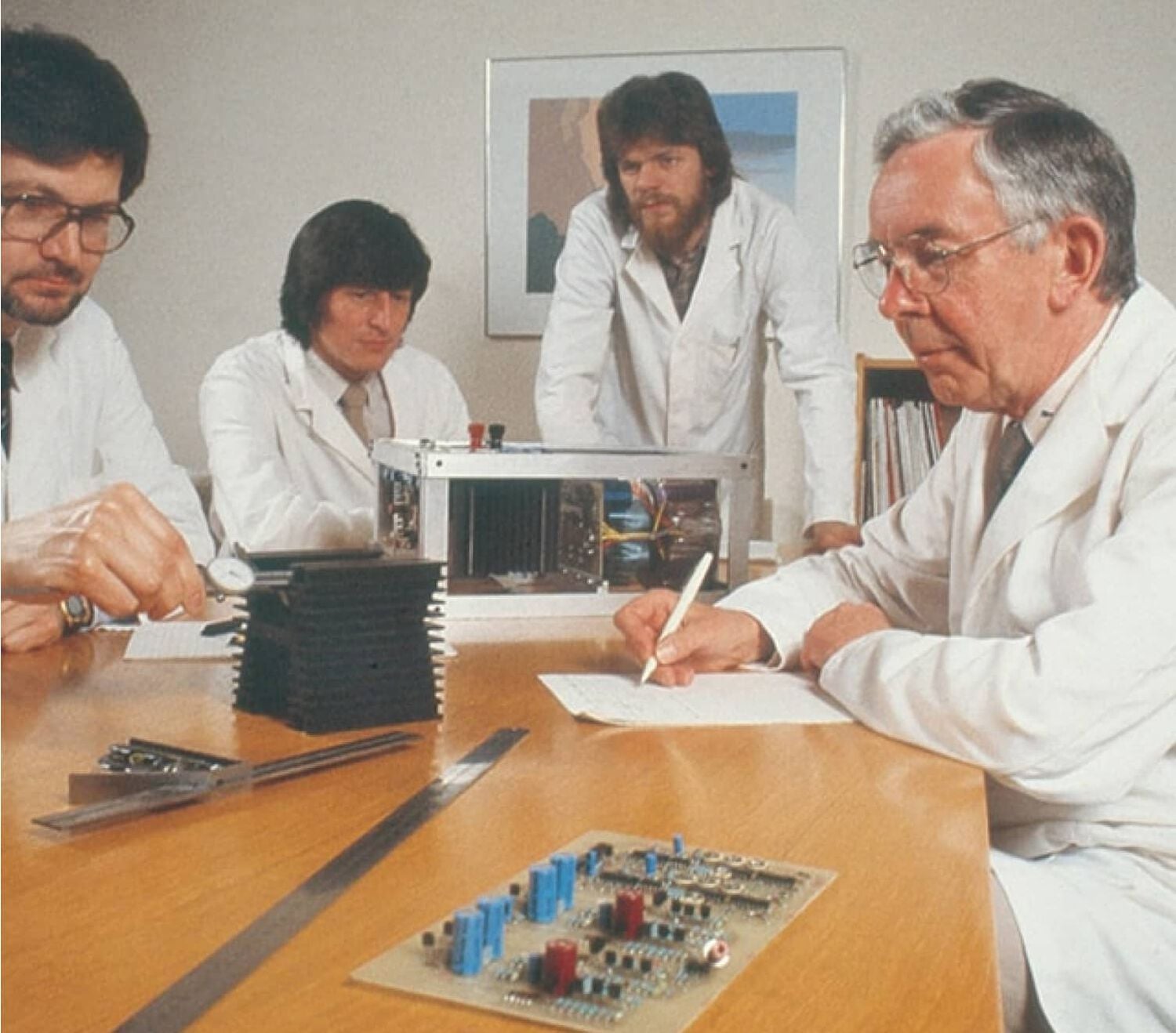 Group of men in lab coats building electronics