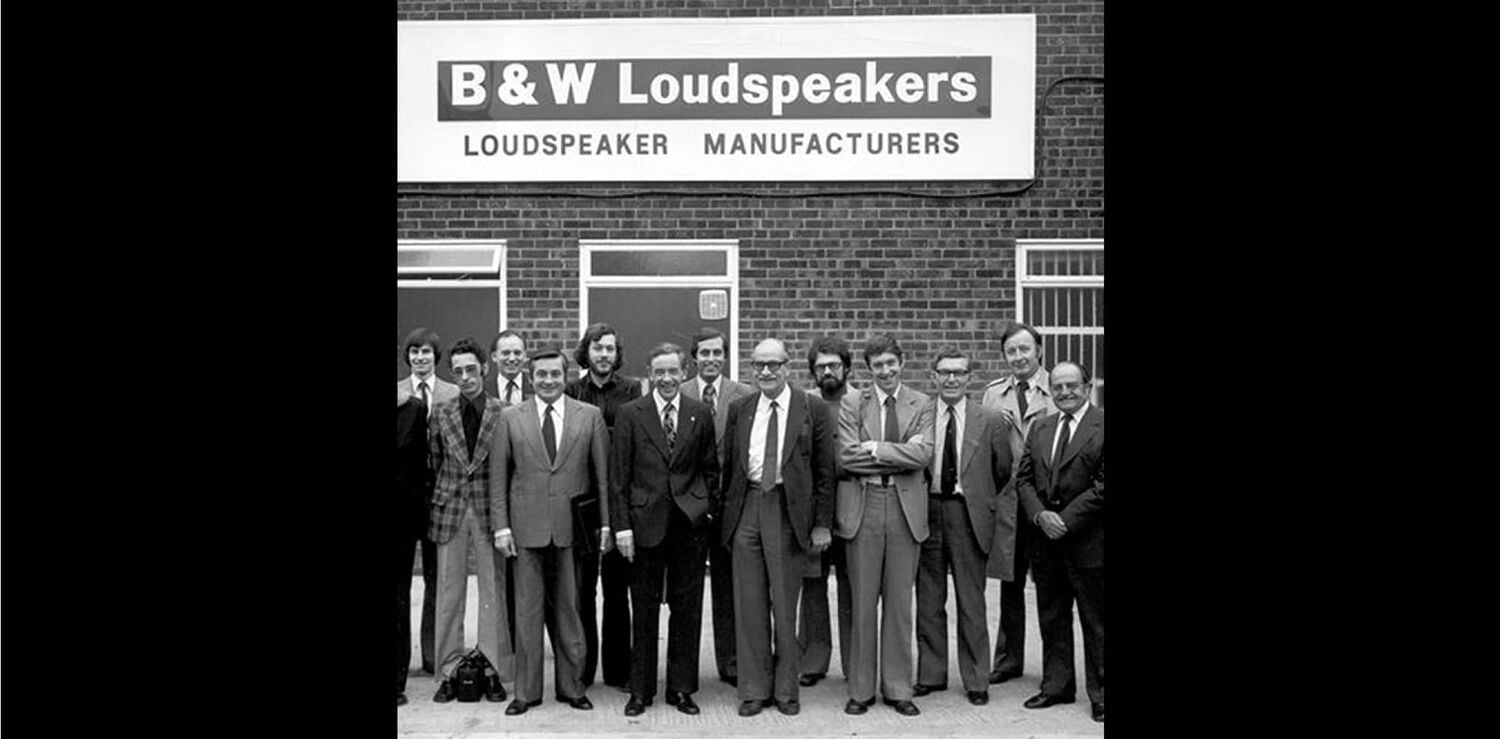 Black and white photo of group of men in front of B & W Loudspeakers store front